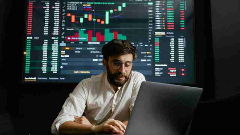 Male analyst studies cryptocurrency trends at a workstation with multiple displays showing market data., tags: deutsche bank und diebold - pexel