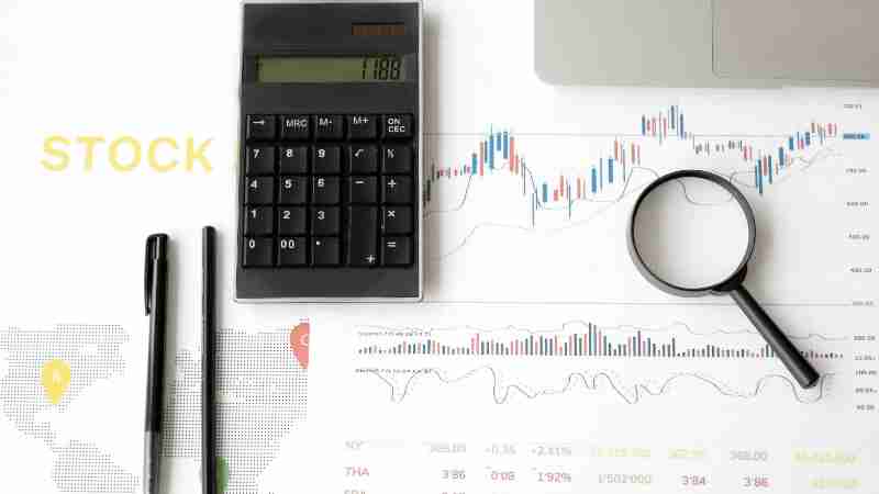 Flat lay of stock market analysis tools including calculator, graphs, and magnifying glass., tags: zeigt - pexel